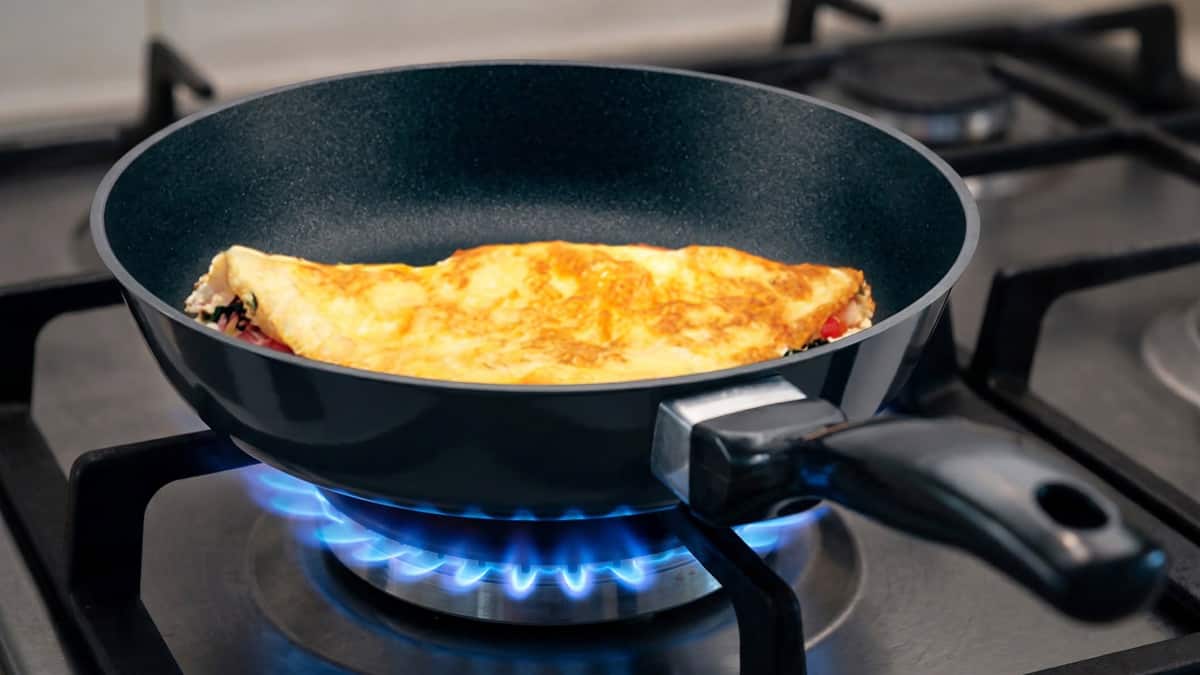 Nonstick frying pan heating on a gas stove while cooking an omelet